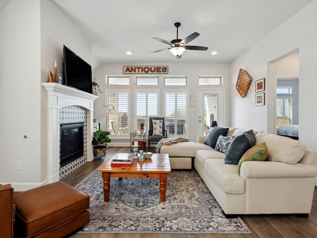 living room featuring a tiled fireplace, ceiling fan, and dark hardwood / wood-style floors