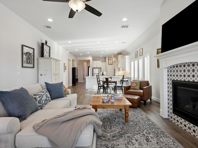 living room with ceiling fan, dark hardwood / wood-style flooring, and a fireplace