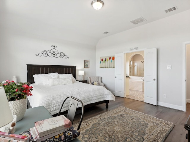 bedroom featuring lofted ceiling, ensuite bathroom, and dark hardwood / wood-style floors