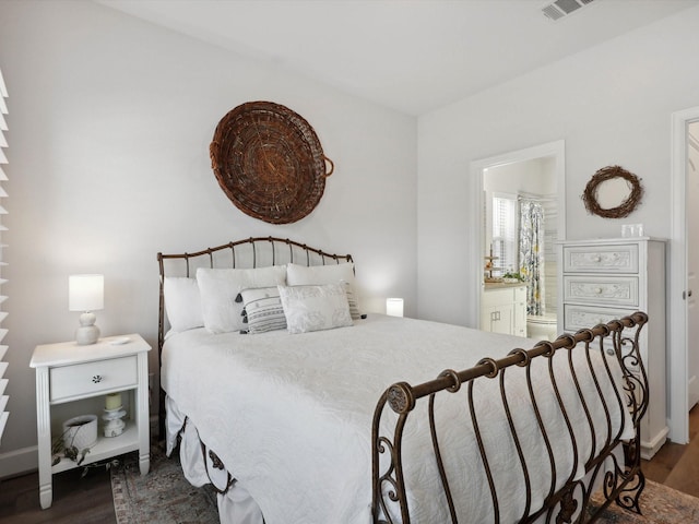 bedroom with ensuite bathroom and dark wood-type flooring