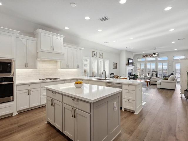 kitchen with kitchen peninsula, stainless steel oven, a center island, ceiling fan, and sink