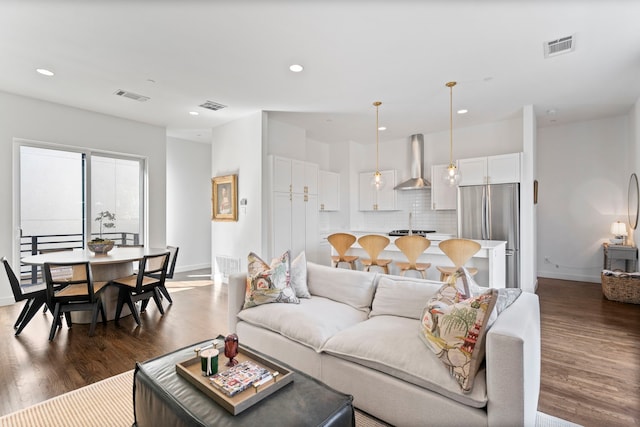 living area with dark wood-style flooring, visible vents, and baseboards