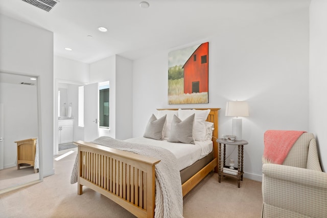 bedroom with light colored carpet and ensuite bathroom