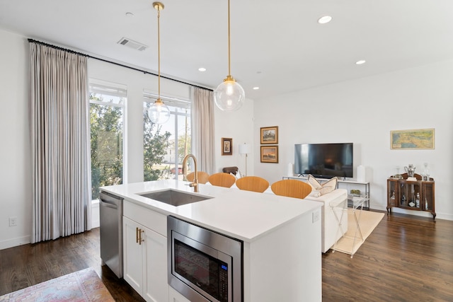 kitchen featuring dark wood-style floors, visible vents, appliances with stainless steel finishes, white cabinetry, and a sink