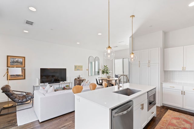 kitchen with stainless steel appliances, a kitchen island with sink, white cabinetry, and sink