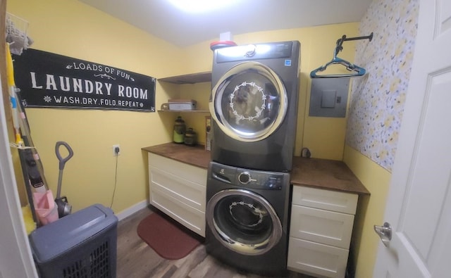 laundry room featuring cabinets, stacked washer / drying machine, and dark hardwood / wood-style floors