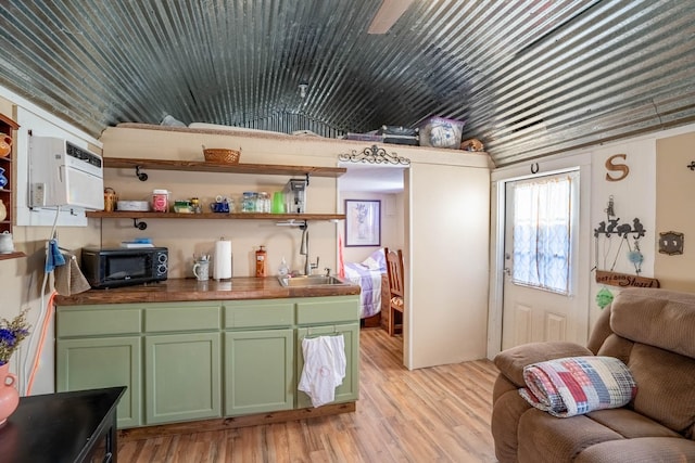 kitchen with green cabinetry, sink, and light hardwood / wood-style flooring