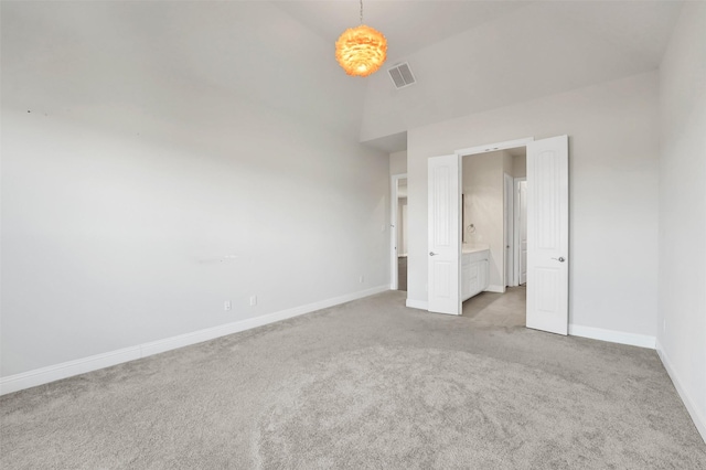 unfurnished bedroom with lofted ceiling, light carpet, and connected bathroom