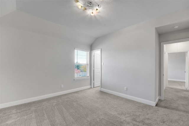 carpeted empty room featuring lofted ceiling