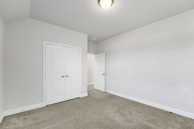 unfurnished bedroom featuring carpet floors, vaulted ceiling, and a closet