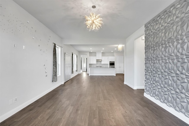 unfurnished living room featuring an inviting chandelier and dark hardwood / wood-style floors