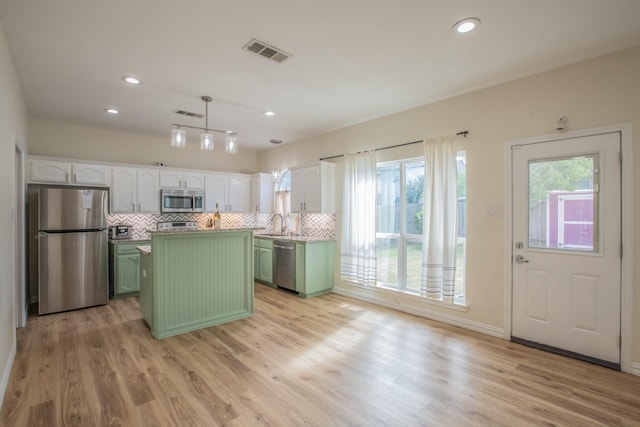 kitchen featuring white cabinetry, stainless steel appliances, hanging light fixtures, green cabinets, and light hardwood / wood-style flooring