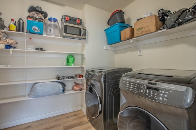 washroom featuring washing machine and clothes dryer and light hardwood / wood-style floors