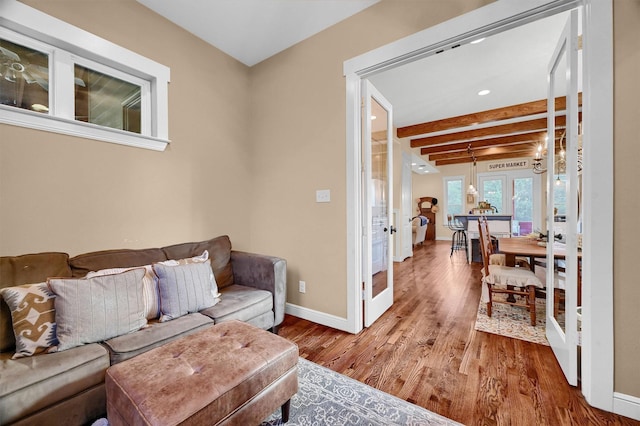 living room with hardwood / wood-style flooring, beam ceiling, and french doors