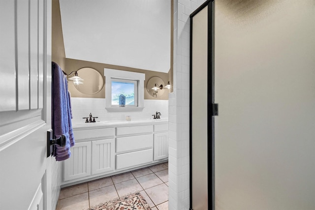 bathroom with vanity, a shower with door, tile patterned flooring, and vaulted ceiling