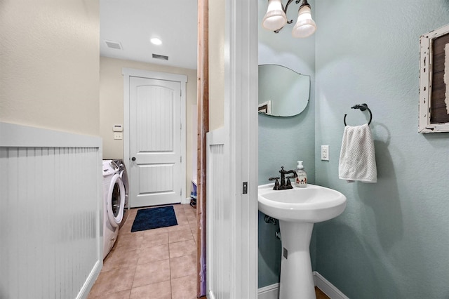 bathroom with tile patterned flooring, washer and clothes dryer, and sink