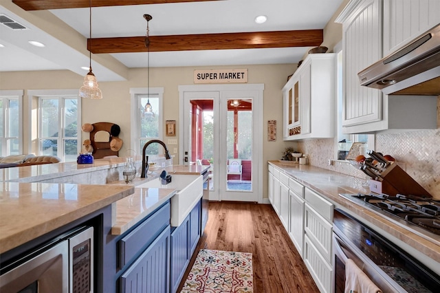 kitchen featuring appliances with stainless steel finishes, beamed ceiling, pendant lighting, sink, and white cabinetry