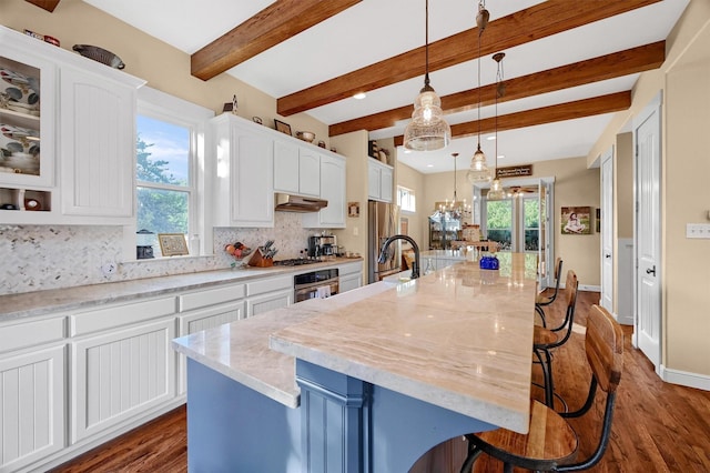 kitchen with a large island with sink, white cabinetry, and hanging light fixtures