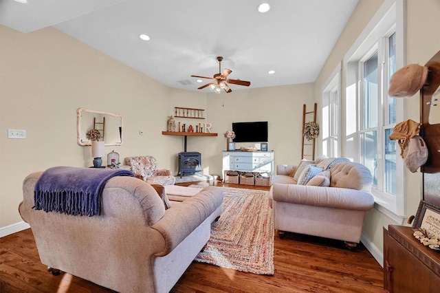 living room featuring ceiling fan, dark hardwood / wood-style flooring, plenty of natural light, and a wood stove