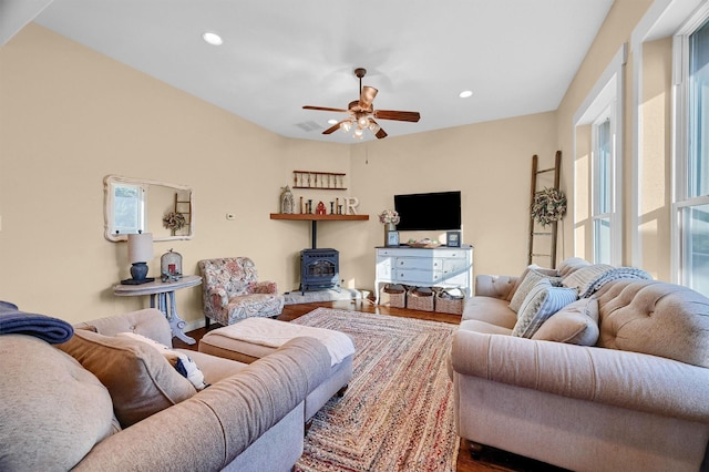 living room featuring hardwood / wood-style floors, ceiling fan, and a wood stove