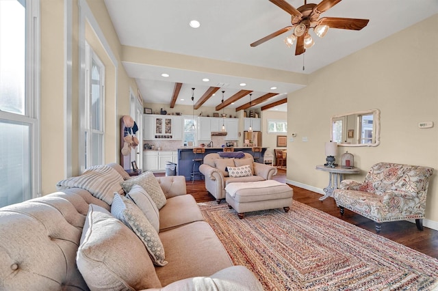 living room featuring ceiling fan, a wealth of natural light, beamed ceiling, and dark hardwood / wood-style floors