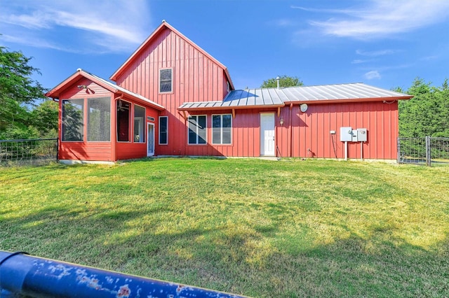 back of house featuring a lawn and a sunroom