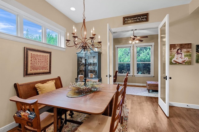 dining area featuring ceiling fan with notable chandelier, french doors, and wood-type flooring