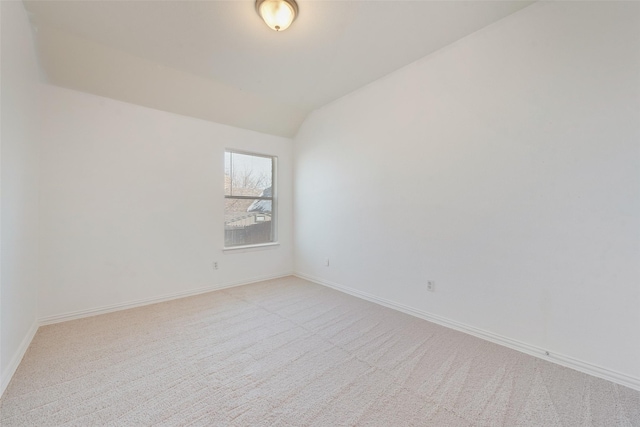 carpeted empty room with vaulted ceiling