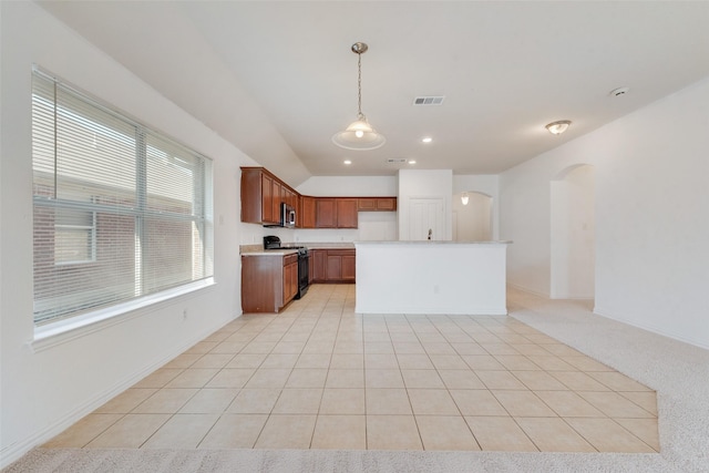 kitchen featuring pendant lighting, gas range oven, light carpet, and a kitchen island