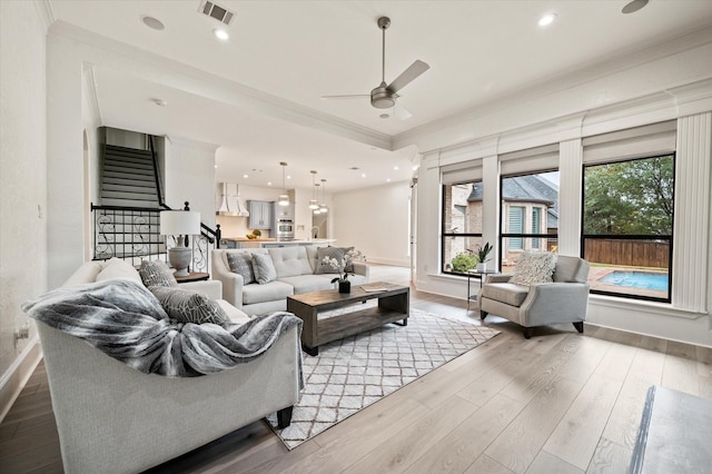 living room featuring ceiling fan, ornamental molding, and light wood-type flooring