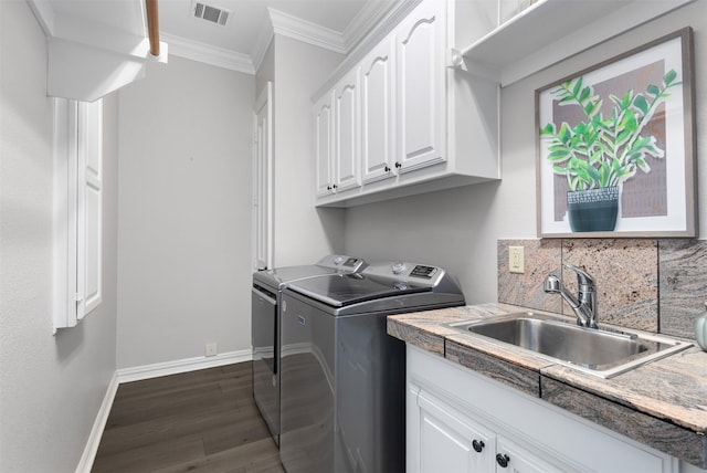 washroom with crown molding, sink, washing machine and dryer, cabinets, and dark hardwood / wood-style floors