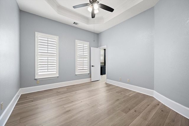 unfurnished room with light wood-type flooring, ceiling fan, a raised ceiling, and ornamental molding