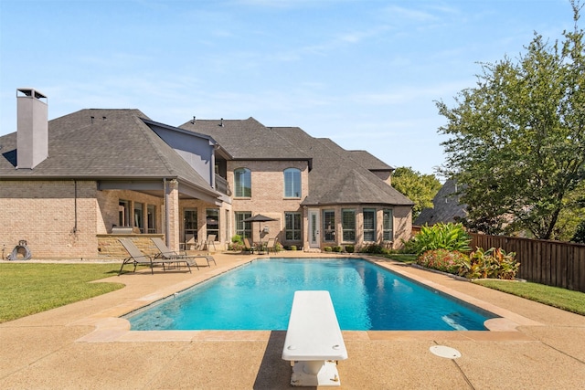 view of pool with a diving board and a patio area