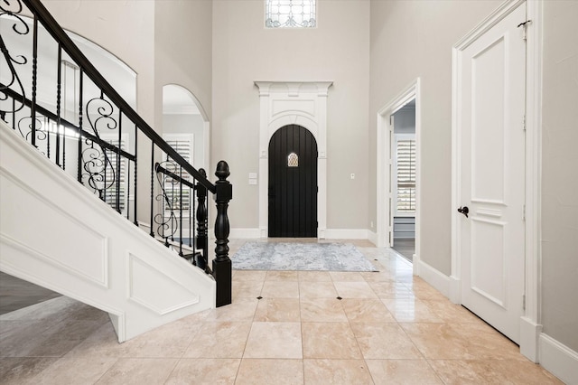 tiled entryway featuring crown molding and a high ceiling