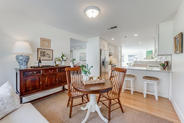 dining space featuring light wood-type flooring and sink