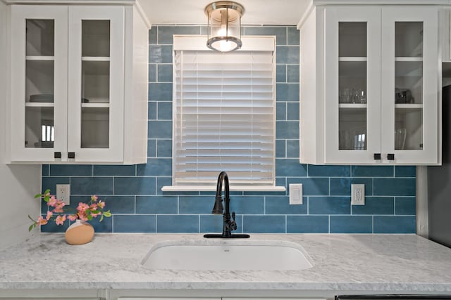 kitchen with white cabinetry, sink, backsplash, and light stone countertops