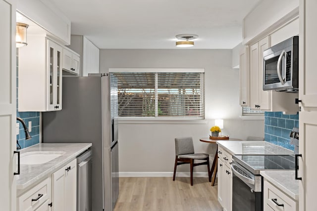 kitchen featuring stainless steel appliances, white cabinetry, sink, and tasteful backsplash