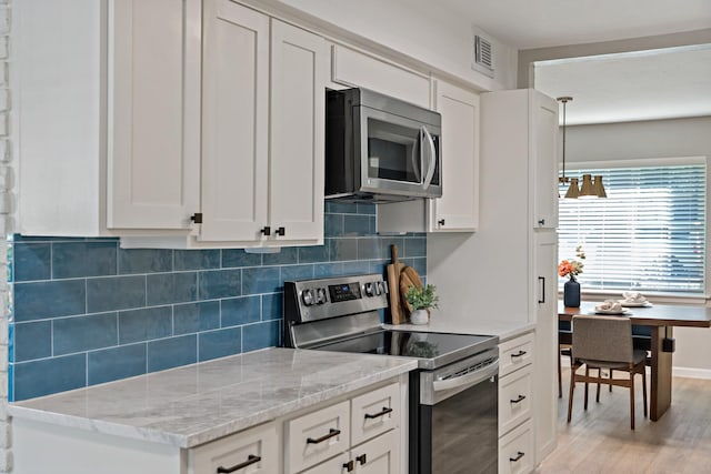 kitchen featuring white cabinetry, appliances with stainless steel finishes, light hardwood / wood-style floors, and backsplash