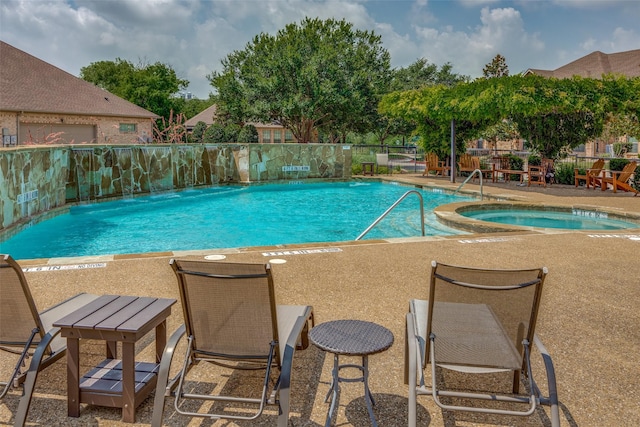 view of pool with a patio area, pool water feature, and a hot tub