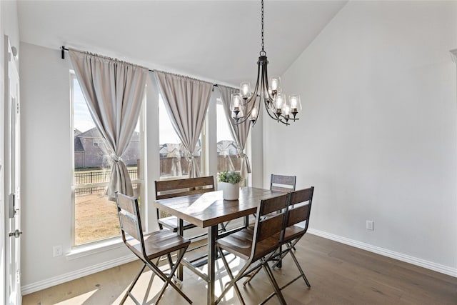 dining space with lofted ceiling, wood-type flooring, and a chandelier