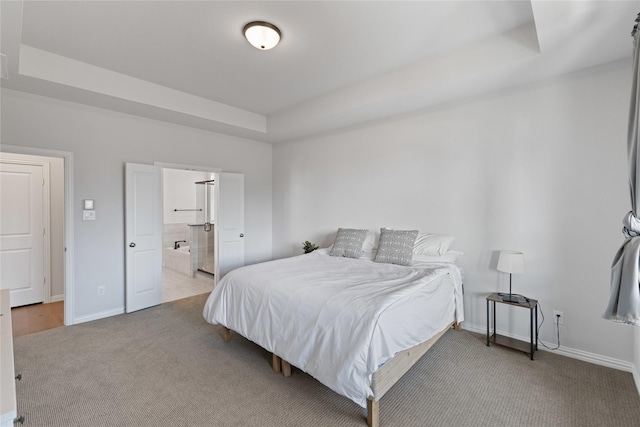 bedroom featuring connected bathroom, carpet floors, and a tray ceiling