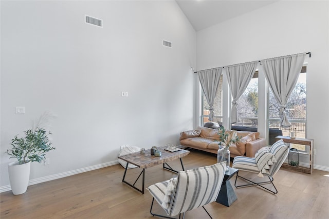 living room with light hardwood / wood-style floors and a towering ceiling