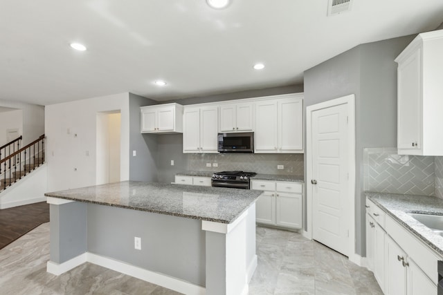 kitchen featuring white cabinets, light stone countertops, a kitchen island, and black range with gas cooktop