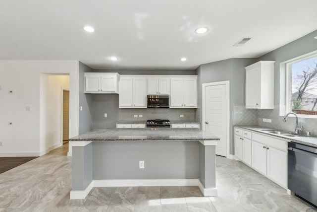 kitchen with light stone countertops, black dishwasher, and a kitchen island