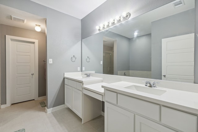 bathroom with a shower with door, vanity, and tile patterned flooring