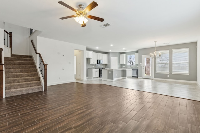 unfurnished living room with ceiling fan with notable chandelier