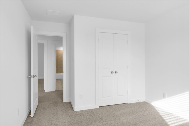 unfurnished bedroom with a closet and light colored carpet