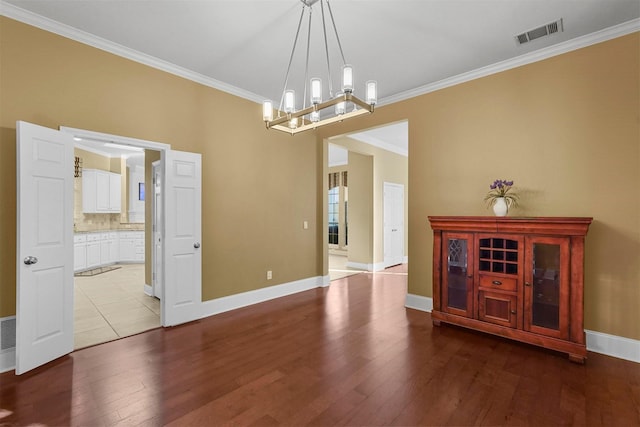 unfurnished dining area with an inviting chandelier, ornamental molding, and light hardwood / wood-style flooring