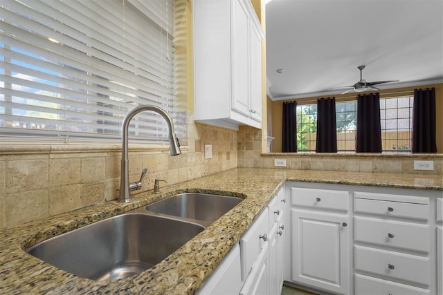 kitchen with sink, white cabinetry, backsplash, and light stone countertops