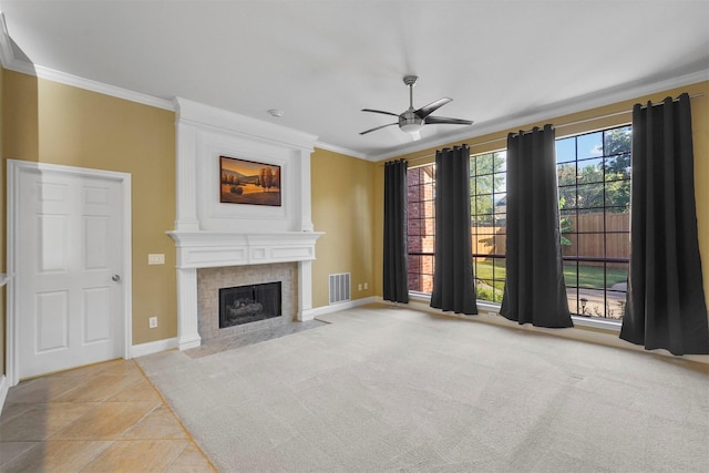 unfurnished living room featuring ceiling fan, a large fireplace, ornamental molding, and light colored carpet